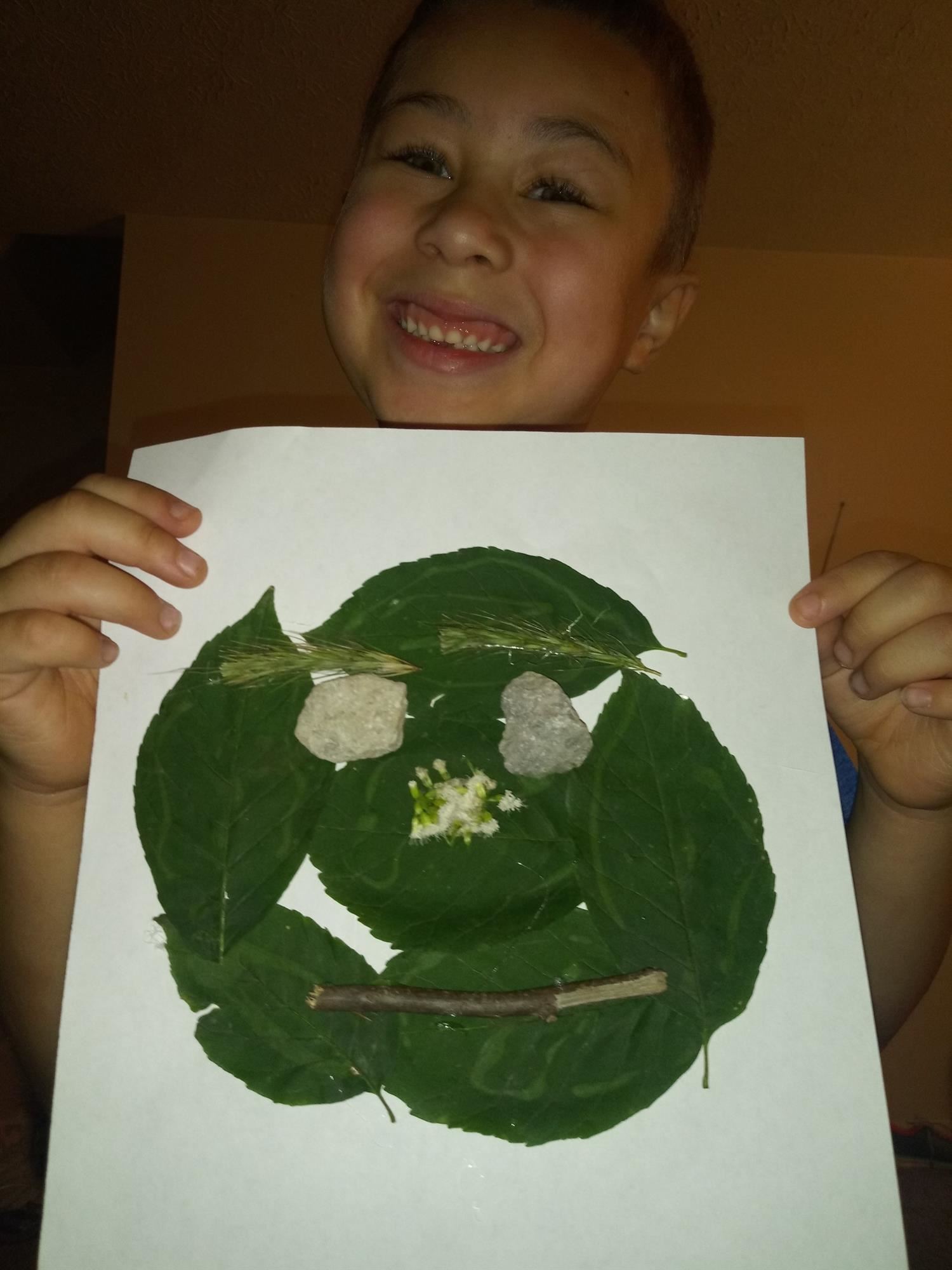Kindergartener Montez Jones shows off her nature face created using leaves, twigs, and rocks 